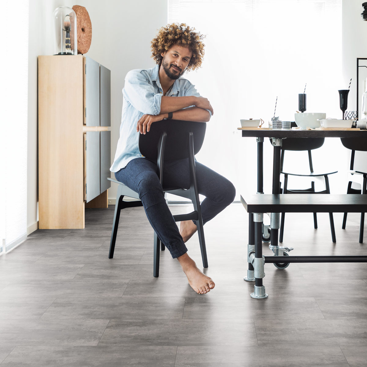 wineo Designboden mit Mann auf einem Stuhl sitzend