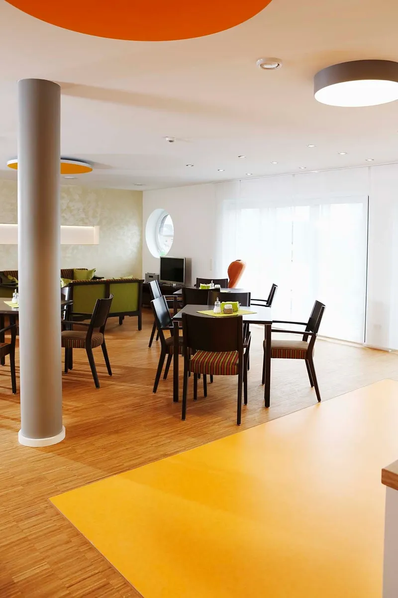 wineo PURLINE Bioboden wineo PURLINE Bioboden im Altenpflege Bodeneblag grün Kantine Esszimmer Stühle Tische orange