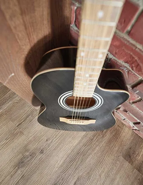 Schwarze Gitarre stehend auf einem modernen Eiche Vinylboden