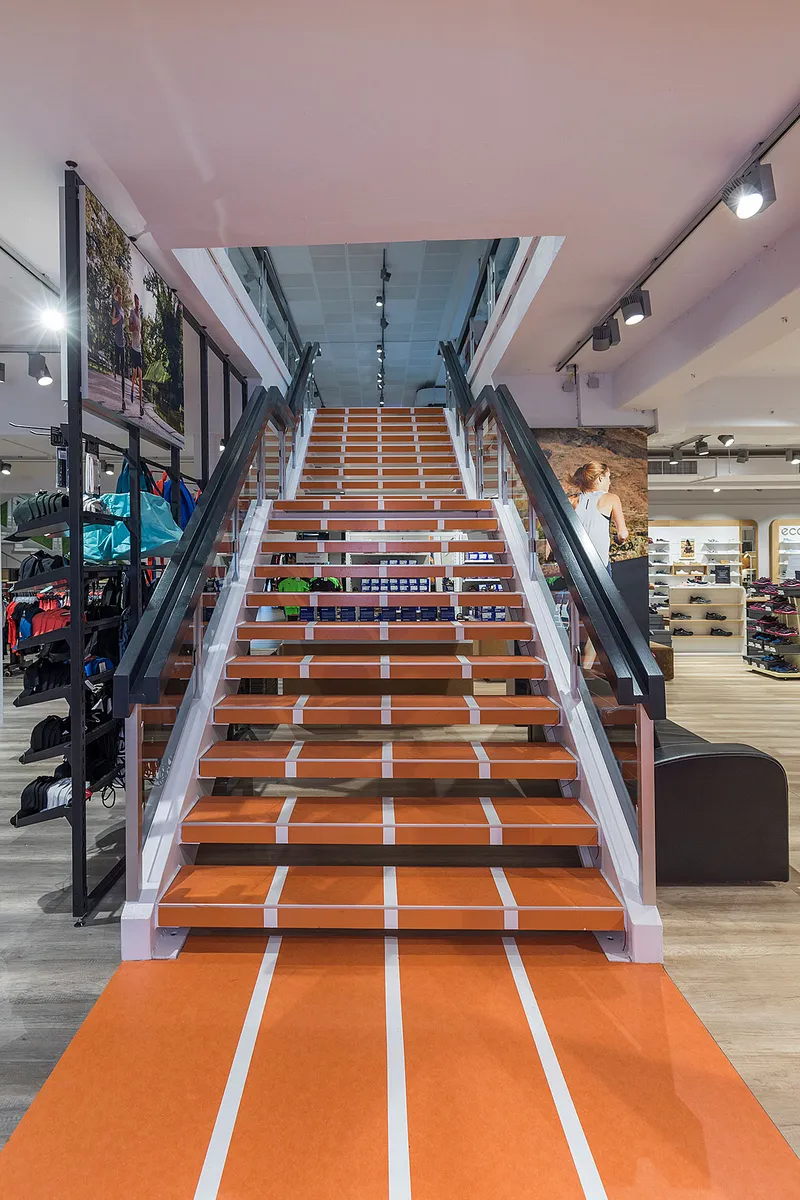 wineo Purline Bioboden  wineo Purline Bioboden Rennbahn Bahnware orange Treppe Sportgeschäft