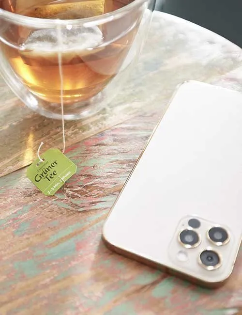 Ein Smartphone und ein grüner Tee stehen auf einem Tisch