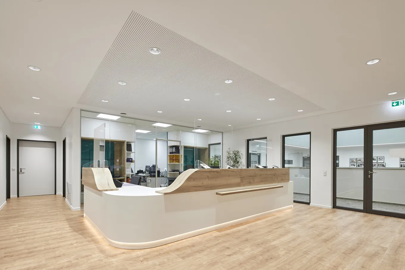 Moderner Empfangsbereich in einer Arztpraxis mit geschwungenem Tresen und rustikalem Holzfußboden